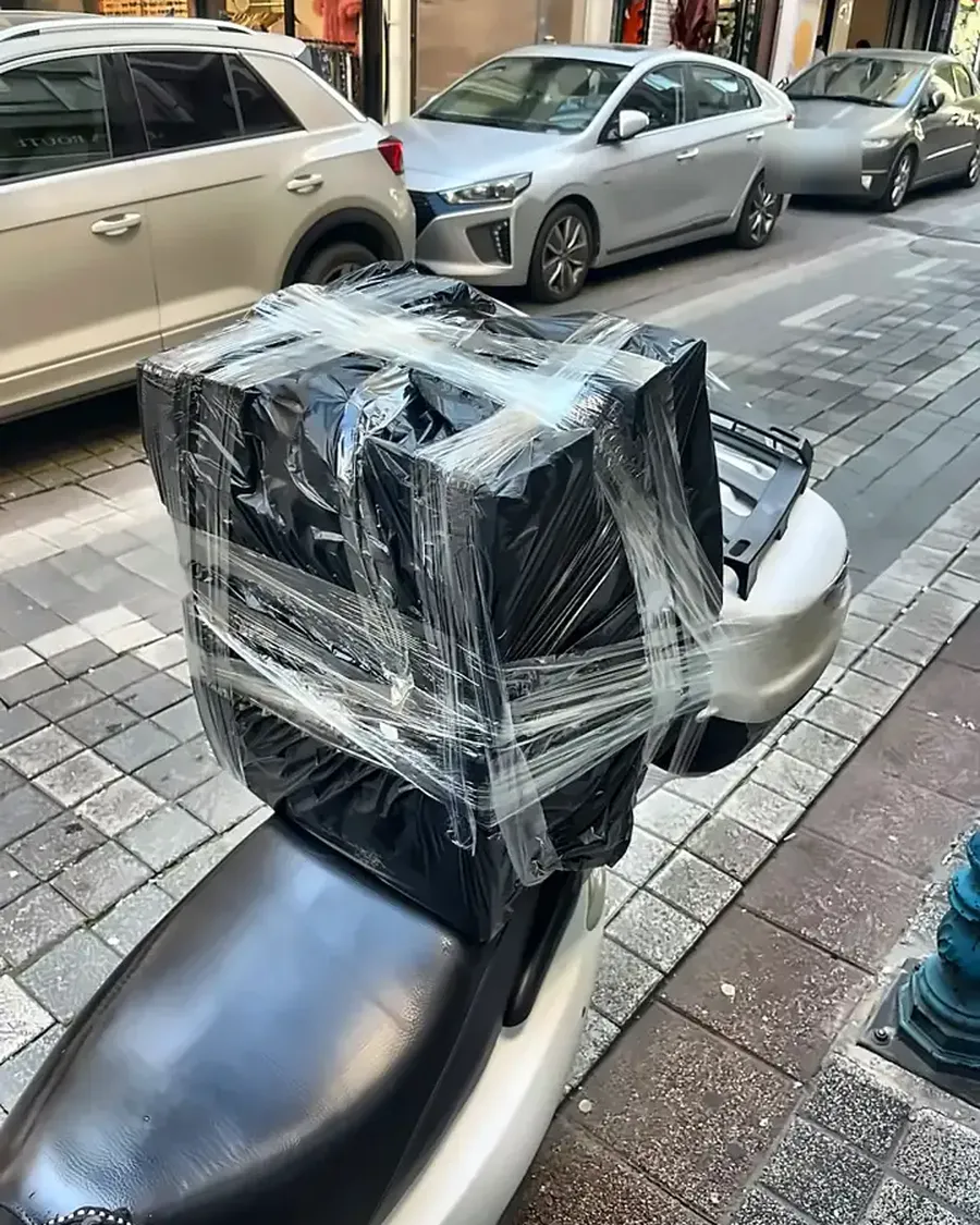 Motorun arkasına sabitlenmiş, streç filmle sarılı koli
